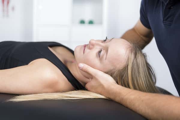 An image of a woman getting a neck adjustment from a chiropractor
